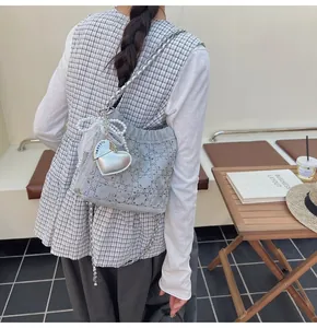 Detalle de bolso acolchado gris con dijes de perlas y etiqueta de corazón plateada en un café