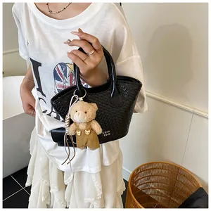 Detail of black woven texture handbag with a cute teddy bear charm and lettered logo