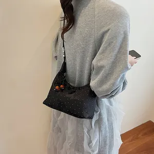 Black hobo bag with white micro-studs and orange bead charms shown on a model