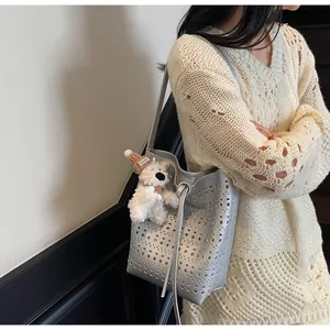 Detail of silver bucket bag with laser-cut hollow design and plush bear charm