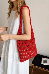 Gros plan sur un sac cabas en maille crochetée rouge au design ajouré pour l'été