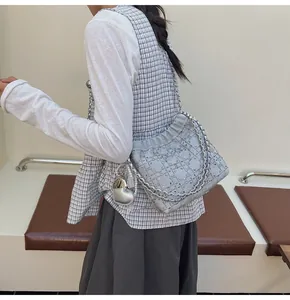 Detalle de bolso tipo saco plateado con pedrería brillante y colgante de corazón