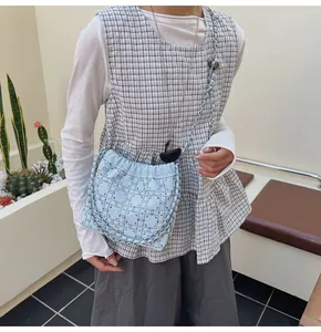 Detalle de bolso tipo cubo azul claro con tachuelas plateadas y correa de cadena