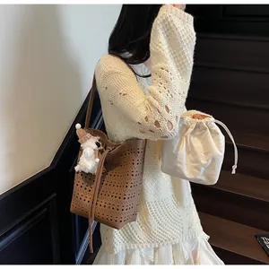 Detailed shot of brown hollow-out bucket bag with a plush charm on a model's shoulder