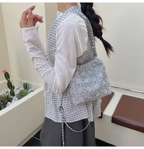Detalle de un bolso tipo cubo plateado con pedrería, cadena y decoración de perlas