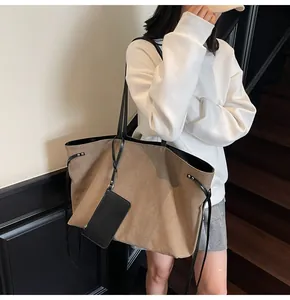 Detail of khaki canvas tote bag with black leather strap and detachable small card pouch