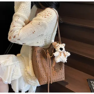 Brown bucket bag with laser-cut hollow pattern and cute plush bear charm detail