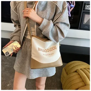 Vue détaillée du sac à bandoulière en toile avec bordure en cuir contrasté et texte