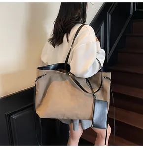 Detail of khaki tote bag with black leather straps and hanging coin purse accessory