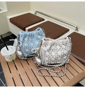 Detalle de bolsos tipo cubo con diamantes en azul y beige con colgantes de perlas