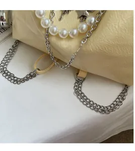 Close-up of cream tote bag with ruched leather texture and silver chain butterfly charm
