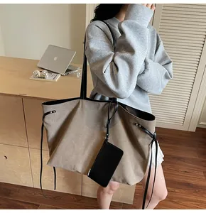 Detail of a large khaki canvas tote bag with black straps and a hanging phone pouch