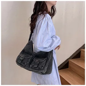 Détail d'un grand sac en jean noir délavé avec poches à rabat et boucles en métal