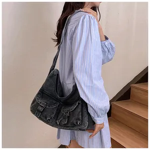 Détail du grand sac cabas en denim délavé avec poches vintage porté par un mannequin femme
