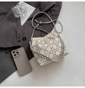 Detalle del bolso saco con diamantes de imitación y comparación de tamaño con móvil