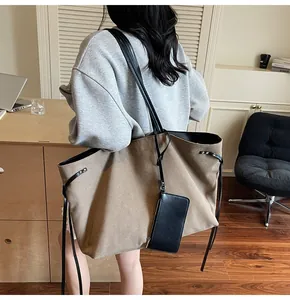 Detail view of large khaki suede tote bag with side drawstrings worn by a model