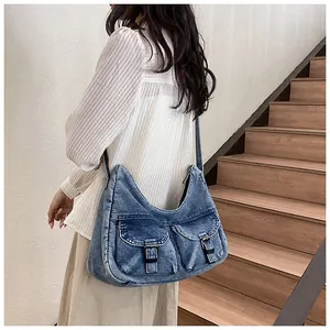 Détail du sac hobo en denim délavé vintage avec poches à rabat et boucles