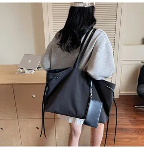 Side view of black canvas tote bag with small zipper pouch shown on model shoulder