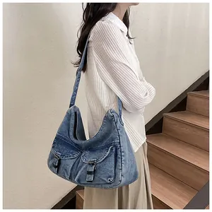 Détail du sac fourre-tout en jean bleu foncé avec poches à boucles en cuir porté par un mannequin