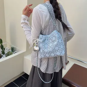 Elegante bolso tote acolchado azul claro con pedrería y cadena mostrado en modelo