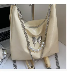 Detail of beige tote bag featuring silver butterfly clasp and elegant pearl chain handle