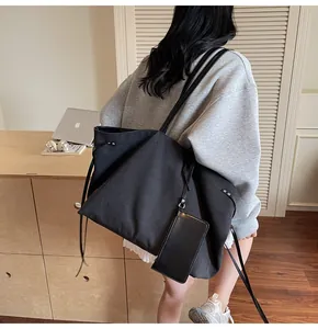 Close-up of black canvas tote bag with side ties and matching small hanging pouch