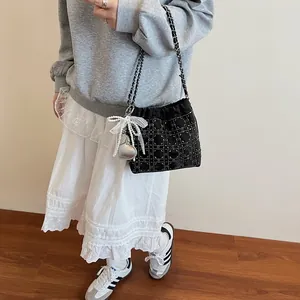 Bolso saco acolchado negro con pedrería, asa de cadena y dije de lazo con perlas
