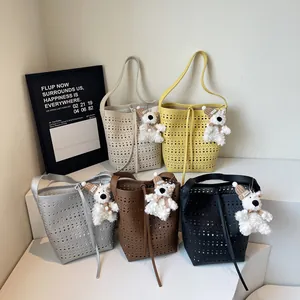 Chic hollow-out bucket bags in five colors with cute teddy bear charms on white steps