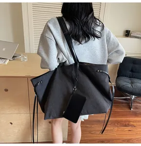Close-up of a black canvas tote bag with side ties and a small detachable zip pouch