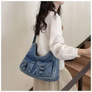 Détail du sac hobo en denim délavé vintage avec deux poches avant et boucles en cuir