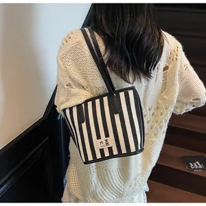 Détail d'un grand sac cabas à rayures noires et blanches avec anses en cuir sur un modèle