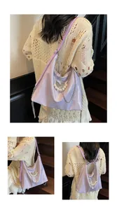 Detail of lavender hobo bag with butterfly charm, pearl chain and glossy leather finish