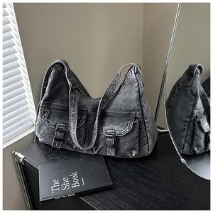 Détail d'un sac à bandoulière en denim délavé avec poches avant et boucles métalliques