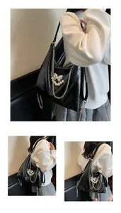 Detail of black glossy leather tote with silver chains and pearl butterfly charm