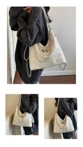 Detail of cream tote bag featuring pearl chain and silver bow knot on crinkled leather