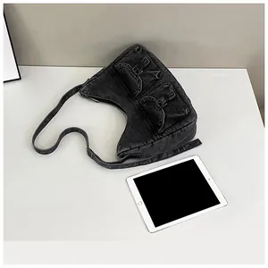 Détail du sac croissant en denim noir délavé avec poches à rabat de style utilitaire