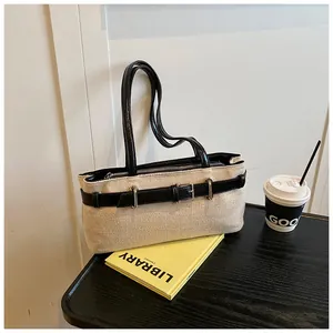 Détail du sac beige tissé avec bandoulières en cuir noir et boucle en métal argenté