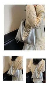Detail of silver metallic hobo bag with pearl chain bow decoration and leather texture