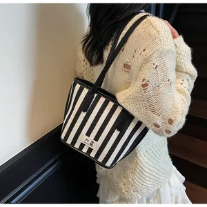 Gros plan d'un cabas rayé noir et blanc avec étiquette sur une tenue en maille
