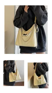 Detail of cream PU leather tote featuring pearl chain, metal link and black bow decoration