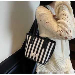 Détail du sac cabas en toile rayée avec finitions en cuir noir et étiquette de marque
