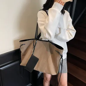 Large khaki canvas tote bag with black leather straps and side drawstring details