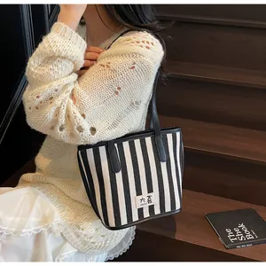 Détail du sac cabas à rayures noires et blanches avec logo dans une scène de style de vie