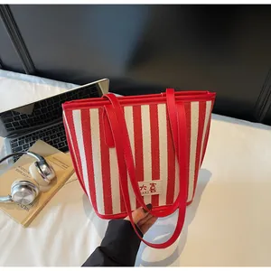 Vue détaillée du sac cabas à rayures rouges avec anses en cuir sur un bureau avec accessoires