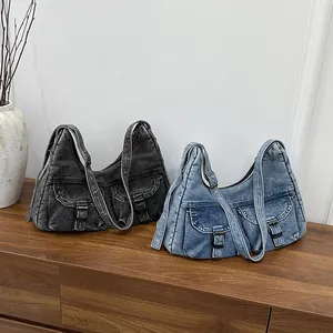 Grands sacs cabas en denim noir et bleu avec boucles métalliques sur une étagère en bois