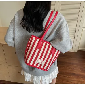 Détail du sac cabas en toile rayé rouge et blanc avec garniture en cuir rouge et logo