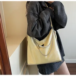 Close-up of a large yellow tote bag with pearly straps and wrinkled leather texture