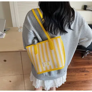 Détail d'un grand sac cabas à rayures jaunes et blanches avec doubles bandoulières
