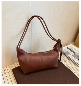 Detail of dark brown leather shoulder bag featuring knotted strap and silver zipper