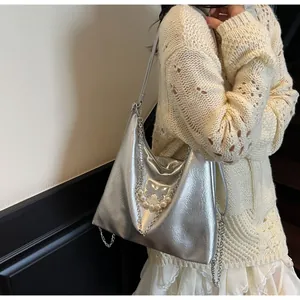 Silver metallic tote bag with chain strap and pearl butterfly charm shown on model